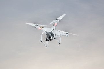 White drone hovering in a bright grey sky