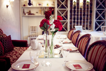 interior of the restaurant,  large table laid for  Banquet, decorated in Burgundy tones