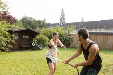 Pärchen ärgert sich mit dem Gartenschlauch