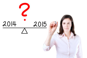 Young business woman writing 2014 and 2015 compare on balance bar. Isolated on white background.
