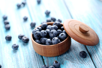 Tasty blueberries in bowl on a blue wooden table