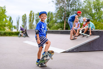 Young boy at a skate park with friends - obrazy, fototapety, plakaty