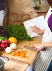 A young woman reading a recipe in the kitchen.
