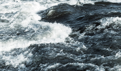 Fast river water with waves, foam and splashes