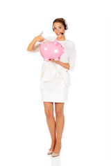 Young businesswoman in headset holding piggybank