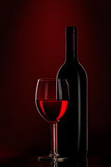 bottle of wine and wine glass on red background