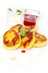 cheesecakes with sour cream and jam on table in restaurant