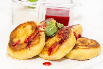 cheesecakes with sour cream and jam on table in restaurant