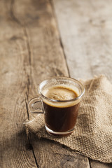 Cup of coffee over a wooden background with hessian sack