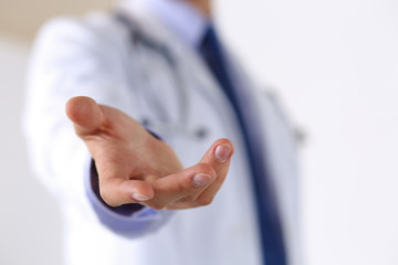 Male medicine doctor offering helping hand in office closeup