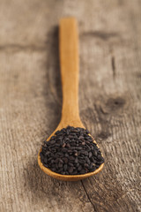 Black sesame seeds on a wooden spoon