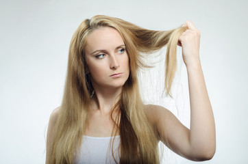 Fototapeta premium Girl looks at the tips of the cross-section of hair