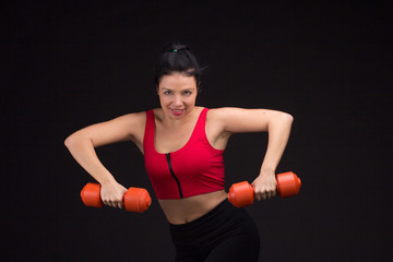 Fototapeta na wymiar Brutal athletic woman pumping up muscules with dumbbells