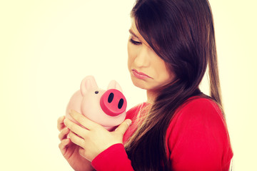 Worried young woman with piggybank.
