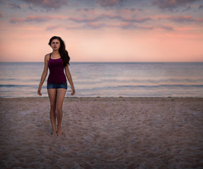 Young woman standing on a beach and enjoying the sun