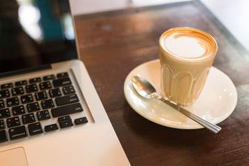 Hot art Latte Coffee in a cup and laptop on wooden table in Coff