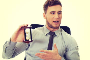Talking businessman holding hourglass.