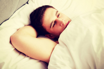Handsome young man lying in bed.