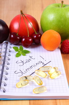 Fruits and tablets supplements with notebook, slimming and healthy food