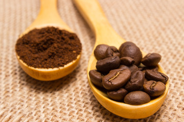 Ground coffee and grains with wooden spoon on jute canvas