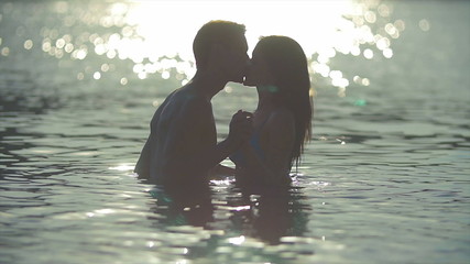 8 in 1 video! The couple (pair) walk on the beach and hug and kiss in the water with sunlight reflection. Real time and slow motion capture. - Powered by Adobe