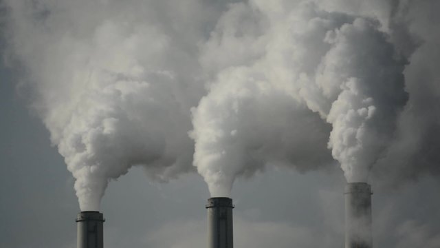A coal-fired power plant emitting carbon dioxide from three smokestacks.