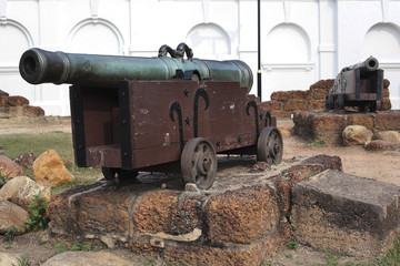 Old medieval artillery canon before a brick wall.