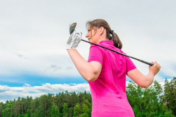 woman golfer view from the back against the sky