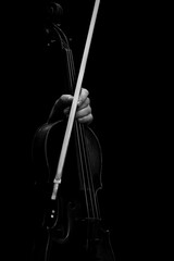 The hand holding the violin in dark colors on a black background