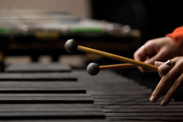 Drum sticks striking the xylophone in close up in dark colors