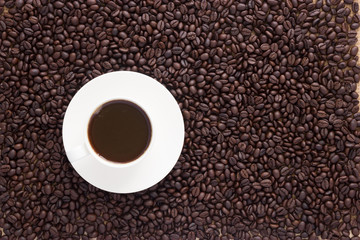 Cup of coffee on coffee beans