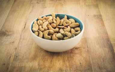 Cashew nuts on bowl on Wood desk background
