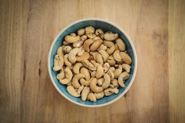 Cashew nuts on bowl on Wood desk background