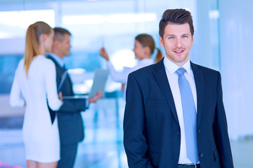 Portrait of young businessman in office with colleagues in the