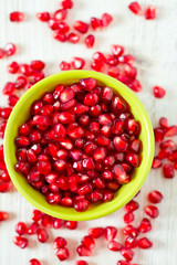 pomegranate seeds in a bowl on wooden surface