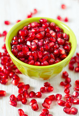 pomegranate seeds in a bowl on wooden surface