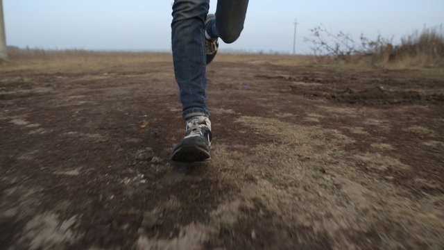 Man running fast on a dirt road. Feet. Shoes. Steadicam shot