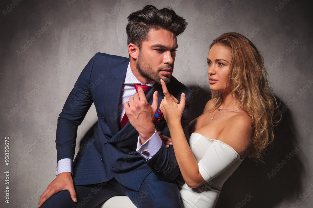 Poster side view of a hot elegant couple sitting in studio