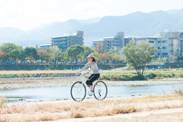 河川敷で自転車に乗っている日本人女性