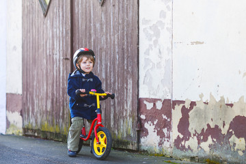 Little boy riding bicycle in village or city