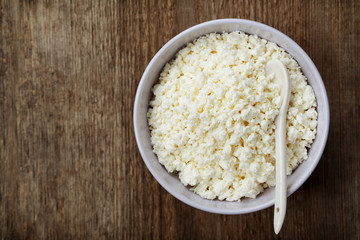 Cottage cheese or curd in bowl on rustic table, rural style,  top view