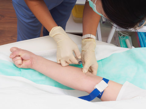 Doctor drawing blood from female patient's arm for examination