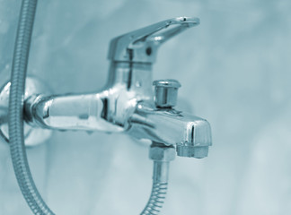 Closeup of faucet in modern bathroom. Selective focus with shallow depth of field. Blue toned.