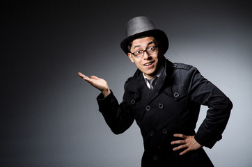 Young man in black coat and hat against gray