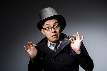 Young man in black coat and hat against gray