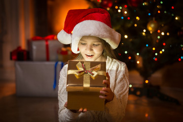 Fototapeta na wymiar cute excited girl looking in magic Christmas box at night