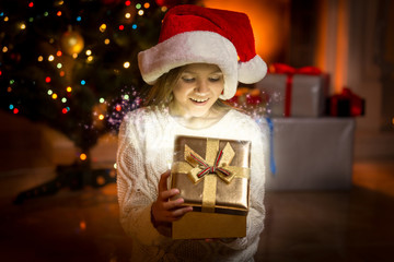 Fototapeta na wymiar little girl posing with glowing golden gift box
