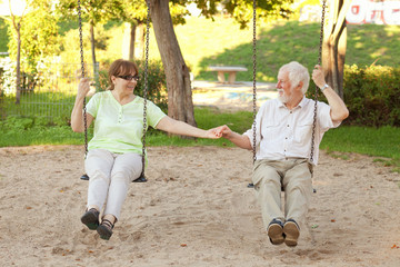 Senior couple swinging in the park