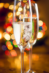 Macro of champagne poured in glasses against Christmas lights