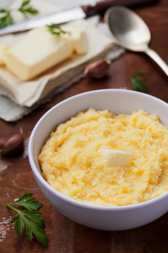 Polenta with butter and cheese in plate on rustic table, traditional Italian side dish